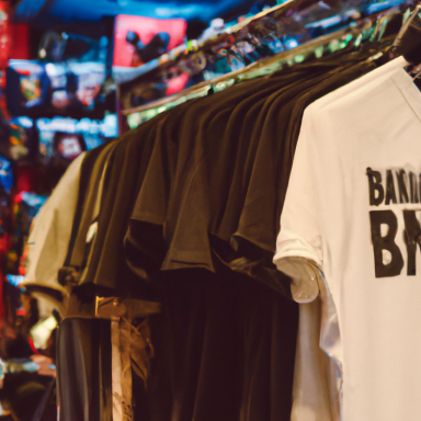 Schwarze T-Shirts hängen nebeneinander, ein weißes in der Mitte.